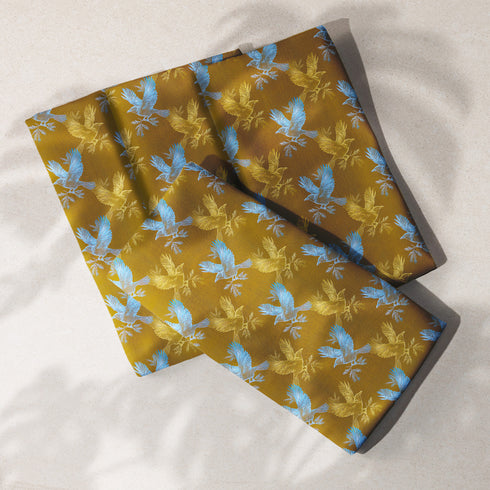 Set of four golden cloth napkins featuring alternating powder blue and metallic gold ravens in flight, sized 18x18 inches.
